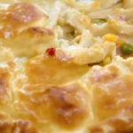 A close-up of a chicken pot pie showing the crispy crust and creamy filling with chicken and vegetables.