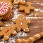 Gingerbread cookies decorated with icing, alongside a candy cane and powdered sugar on a rustic table.