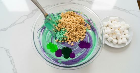 Folding crispy rice cereal into tinted marshmallow mixture