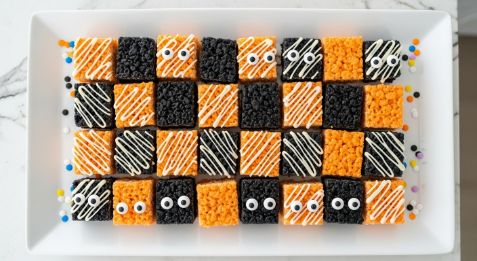 Checkerboard arrangement of orange and black Rice Krispie squares on a platter