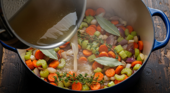Adding broth and herbs to Italian Wedding Soup with Fall Vegetables