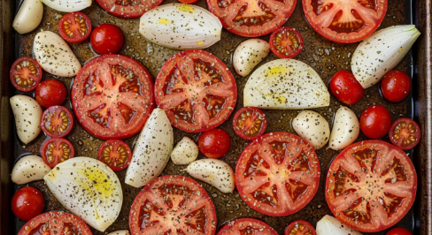 Tomatoes, onion, and garlic on a sheet pan for Roasted Tomato Basil Soup