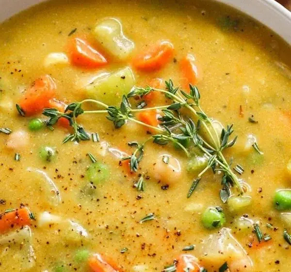 A bowl of comforting one-pot creamy vegetable soup with fresh vegetables.
