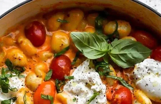 Bowl of creamy tomato gnocchi with fresh basil and cheese on top