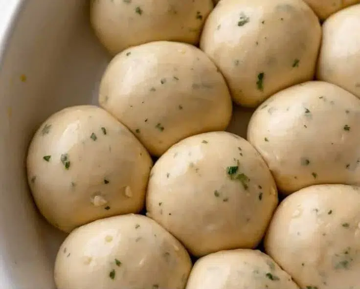 Freshly baked garlic bread rolls served on a wooden platter.