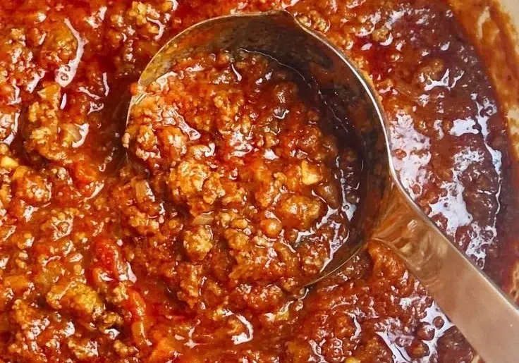 A bowl of perfect Italian meat sauce served with pasta and herbs.