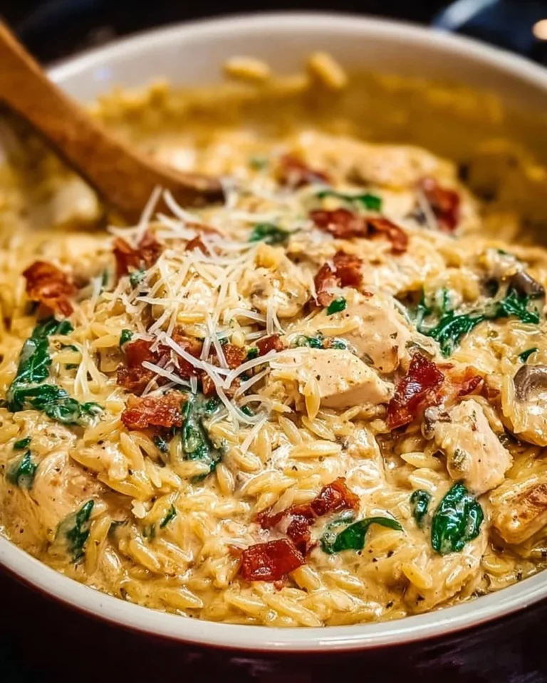 Bowl of Slow Cooker Creamy Tuscan Chicken Orzo garnished with herbs.