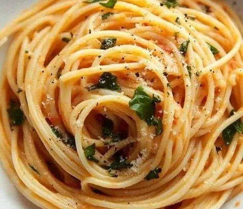 Plate of Tomato Butter Pasta topped with fresh herbs and parmesan cheese
