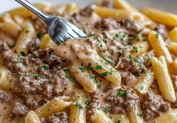 Bowl of Slow Cooker Creamy Garlic Beef Pasta garnished with fresh herbs.