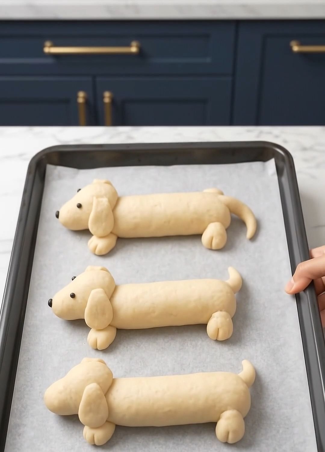 Assembled dachshund-shaped bread rolls on a parchment-lined tray